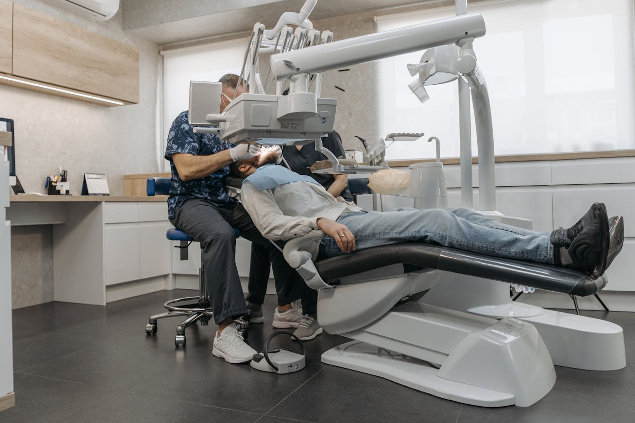 A dentist examines a patient using advanced dental equipment in a modern clinic setting.